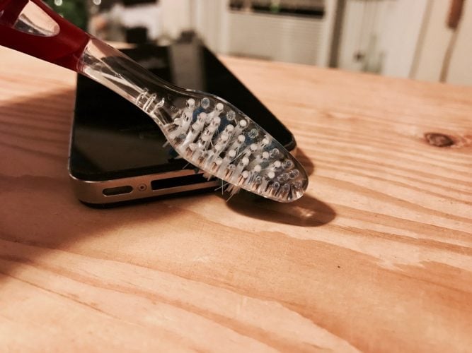 Cleaning an iPhone microphone with a toothbrush. 