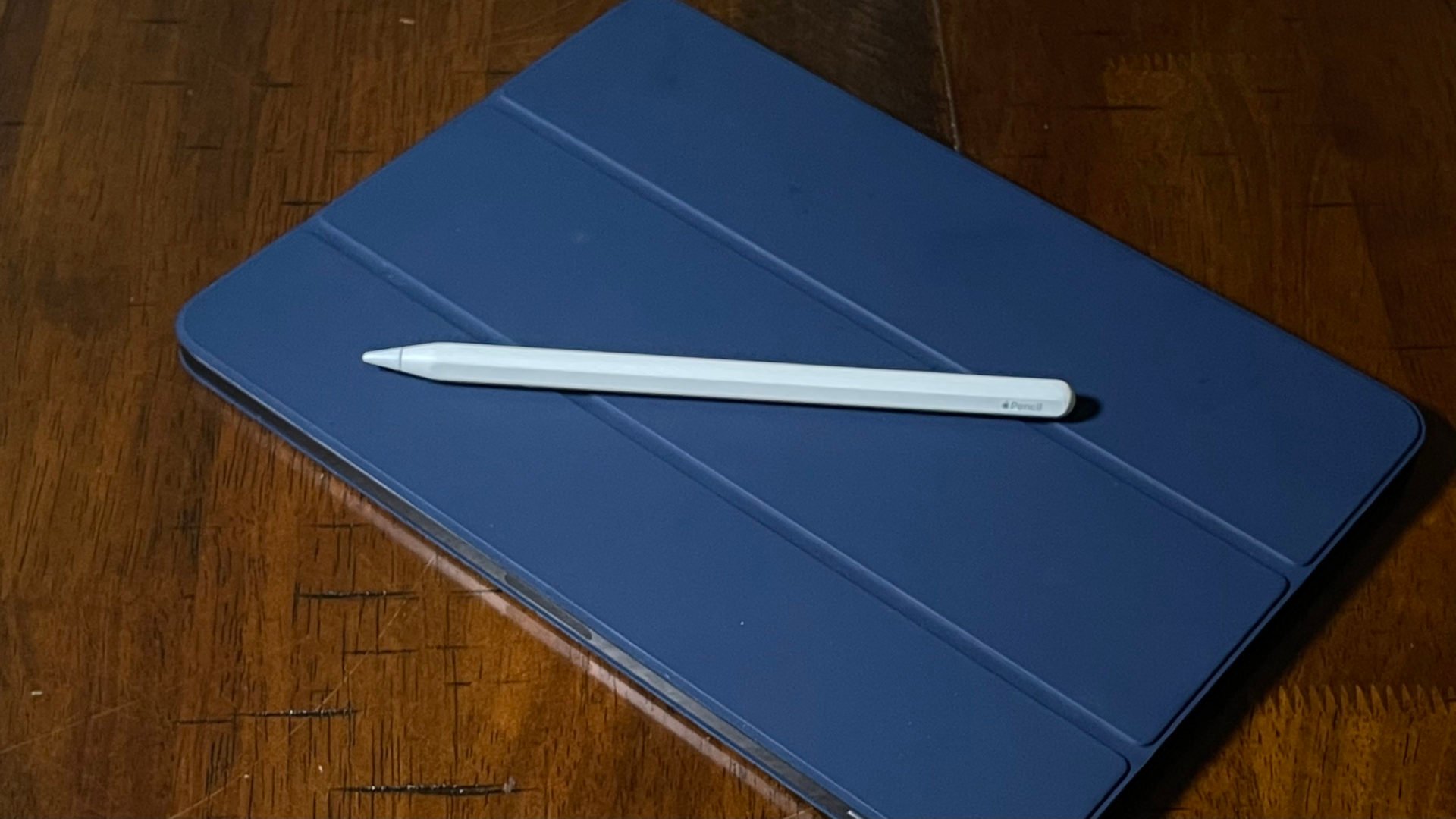 Apple Pencil on top of an iPad with a leather case. 